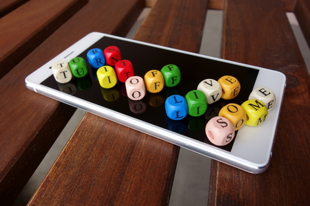 Turn it off and live some - motivational slogan, colorful beads with letters on a mobile phone