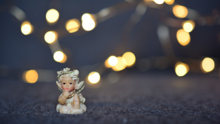 Little cherub against blurred Christmas lights
