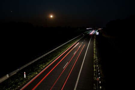 Late night traffic on the motorway with a full moon in the backgroundの写真素材