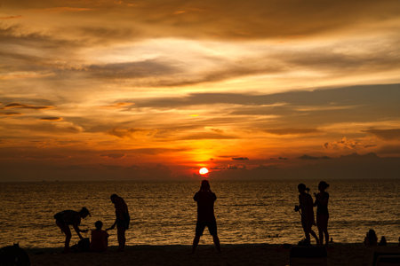 Man taking photo of sunset on the beachの写真素材