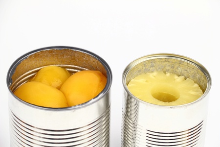 The tins with peaches and pineapples on the white backgroundの写真素材