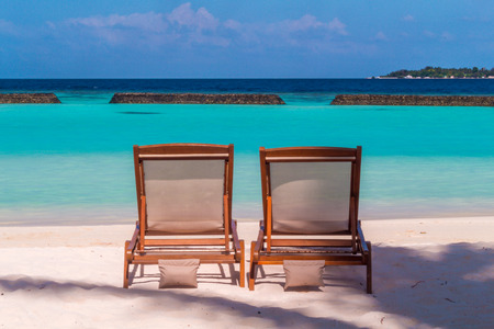 Two wooden sun loungers at the beach in Maldivesの写真素材