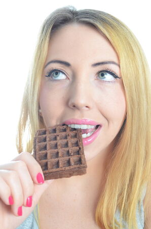 Young woman eating chocolate waffle isolatedの写真素材