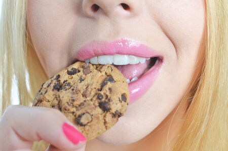 Young woman eating cookie isolatedの写真素材