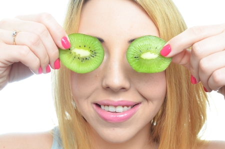 Young woman with fresh kiwi fruit isolatedの写真素材