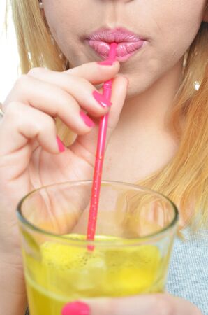 Woman drinking orange juice isolatedの写真素材