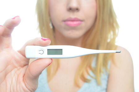 Young woman taking temperature and pills isolatedの写真素材