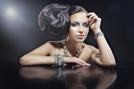 Portrait of beautiful brunette woman wearing jewellery at black mirror tableの写真素材