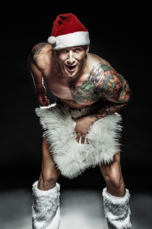 Funny handsome muscular man posing in santa claus hat, looking at camera.の写真素材