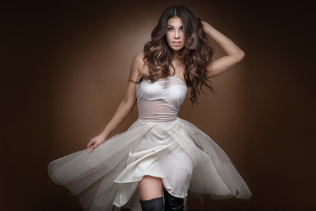 Fashionable sexy young woman posing in white dress, looking at camera.の写真素材