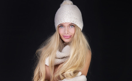 Blonde sexy woman in fashionable winter cap, scarf, gloves. Studio photo.の写真素材