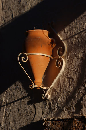 Clay vase hanging on a wall in the shade of the sunの写真素材
