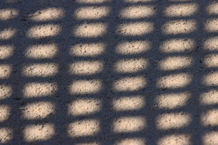 The shadow of the fence on the sand. Abstract background for design.の写真素材