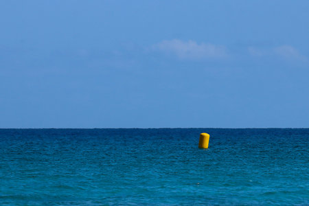 Yellow buoy on the sea, blue sky and white clouds background.の写真素材