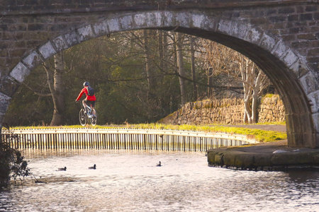 Cyclist riding bicycle on the bridge over the river, UKの写真素材