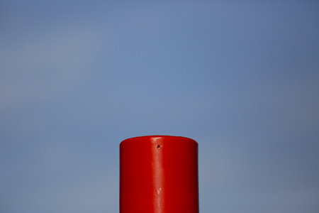 Close-up of a red plastic pole against the blue sky.の写真素材