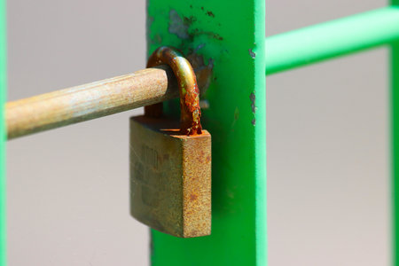 Padlock on green metal fence, close-up of padlockの写真素材