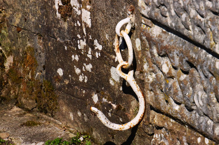 Old rusty chain hanging on a stone wall, closeup of photoの写真素材
