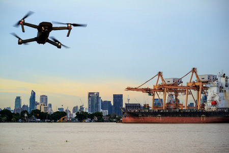 Modern RC Drone / Quadcopter with camera flying on container cargo ship at shipping port. double exposureの写真素材