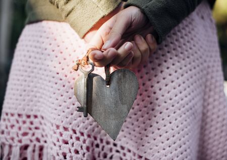 Girl holding a heart key behind her backの写真素材