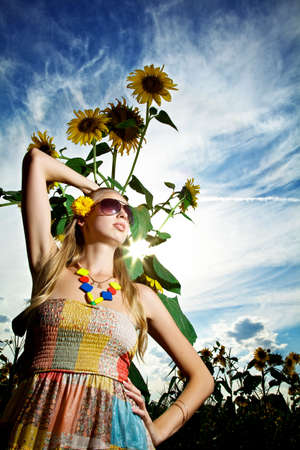 Young pretty woman on a sunflowers and sky backgroundの写真素材