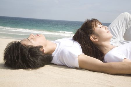 Japanese couple lying on a beachの写真素材