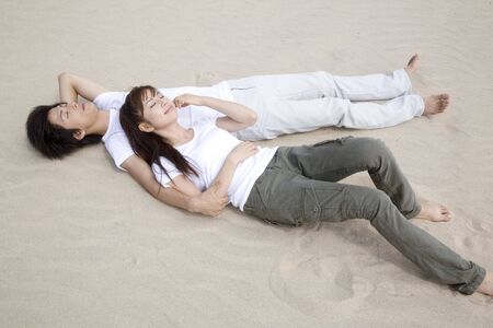 Japanese couple lying on a beachの写真素材