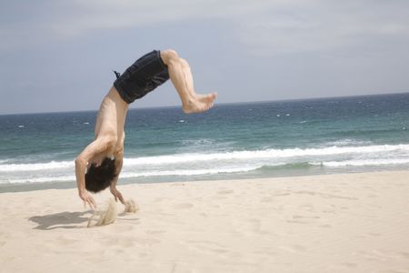 Japanese man doing gymnastics on a beachの写真素材