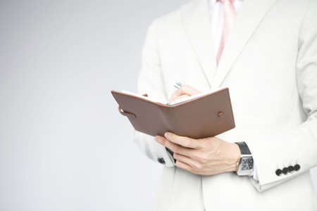 Office worker writing something to the pocket notebookの写真素材