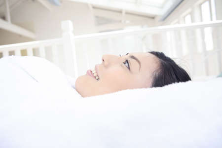 Woman lying down on the bedの写真素材