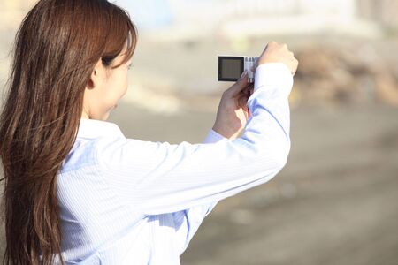 Japanese woman shooting a photo on a beachの写真素材