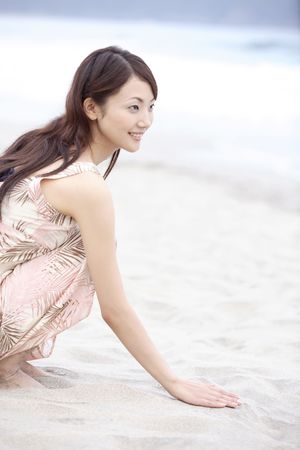 Japanese woman sitting on a beachの写真素材