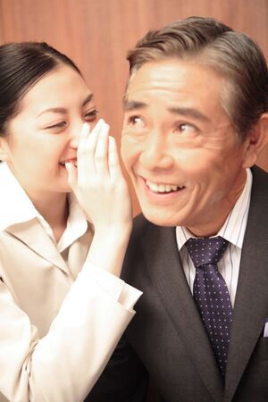 Office lady talking secretively to executiveの写真素材