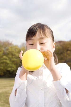 Japanese girl blowing up a balloonの写真素材