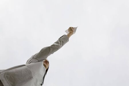 Japanese young man trying to throw the paper planeの写真素材