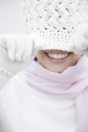 Woman covering the face with a knit hatの写真素材