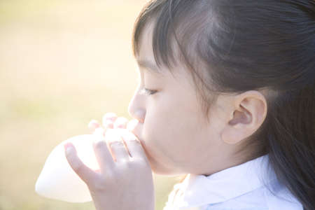 Japanese girl blowing up balloonの写真素材