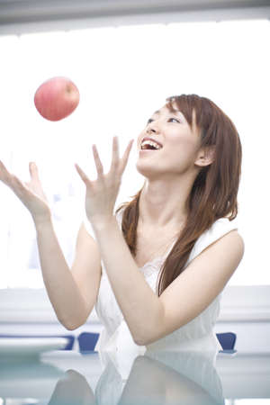 Japanese woman throwing an apple with joyの写真素材