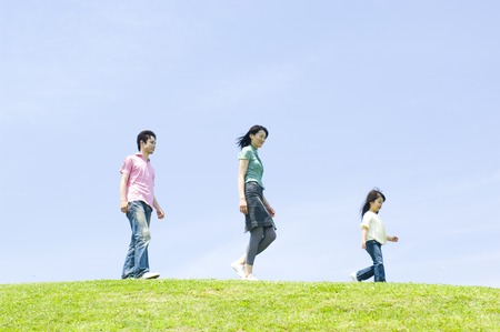 Family walking side by side up the hillの写真素材