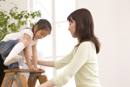 Mother to support the girl to climb to the stepladderの写真素材