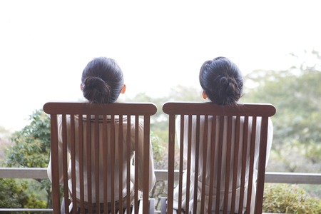 Sit on the edge of the chair 2 women of Rear Viewの写真素材