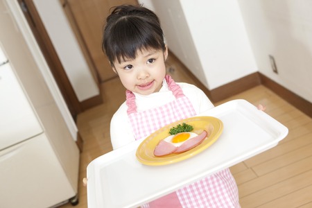 Girl carrying a dish of ham and eggsの写真素材