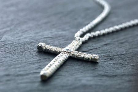 The cross accessory made by silver on the table.の写真素材