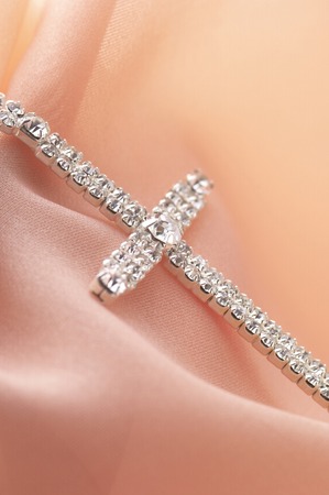 The cross accessory made by silver on the pink fabric.の写真素材