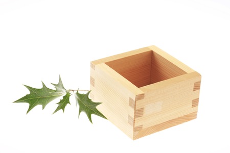 A measure box and holly tree leaf on the white floor.の写真素材