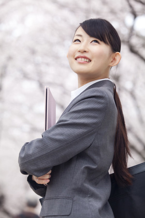 OL you smile looking back under the cherry treeの写真素材