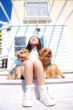 Girl sitting with two animals Norfolk terrier on the terrace