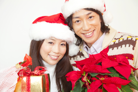 Couples smile with a Christmas gifts and poinsettiaの写真素材