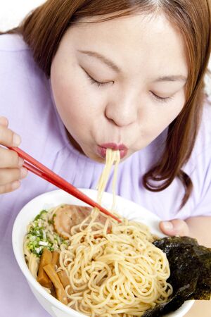 Overweight woman eating ramen noodlesの写真素材