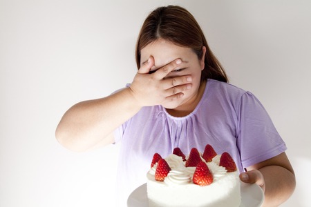 Overweight women tempted to cakeの写真素材